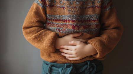 A young boy holding his stomach, feeling uncomfortable from overeating junk food.の素材