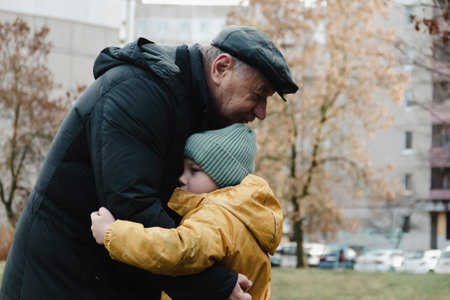 An elderly man, a grandfather, says goodbye to his little grandson after an active and eventful day