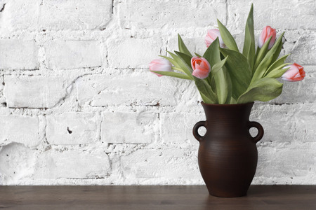 pitcher with tulips on a background of a brick wallの写真素材