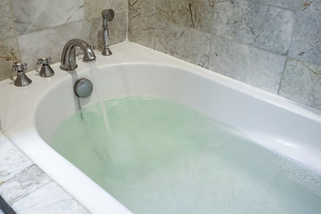 Stainless Faucet with white bathtub in bathroom.の写真素材