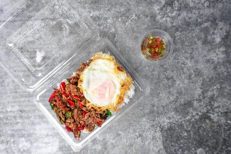 Top view  Rice topped with stir-fried beef and holy with egg basil on the gray concrete table,...