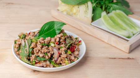Close up Thai spicy minced pork salad or Larb moo white and vegetable side dish on wooden table.の写真素材