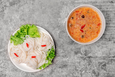 Top view rice vermicelli noodle with curry soup on the gray concrete table.