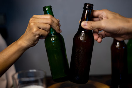 Two Friends Toasting With Bottle Of Light Beer. Hands lifting two beer bottle and happy enjoying...