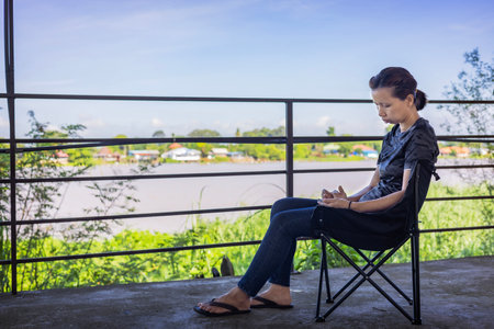 Woman sitting in a camping chair on the background of a river. Vacation time.の写真素材