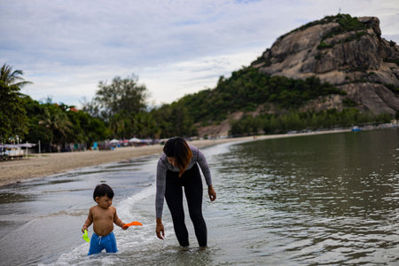 Mother and son playing on the beach at the day time. Vacation time.