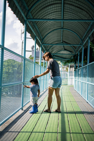 Mother and son looking animal  in an outdoor zoo. They are standing next to a cage with animals.