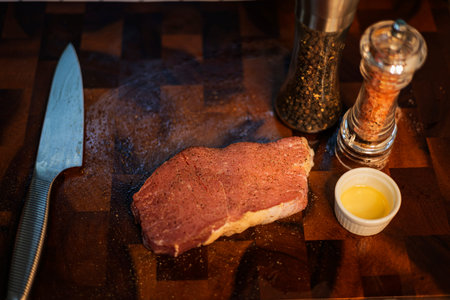 Raw meat steak with seasonings on wooden cutting board.の写真素材