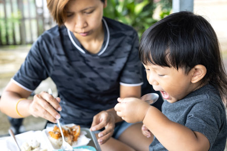 The boy scooped food into his mouth by himself.の写真素材