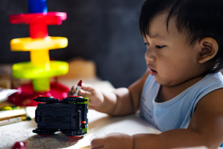 Little boy painting toy car in living room.
