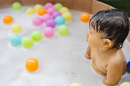 Little child with plastic ball in foamy bath.の写真素材