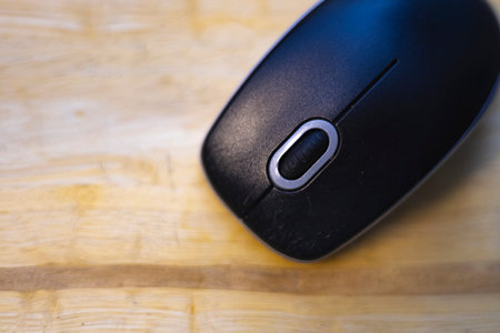 Close up view of black wireless mouse placed on wooden table.の写真素材