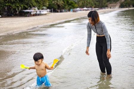 Mother And Child Walk In Beach With Washing Their Feet, Background for wallpaper in summer and lifestyle scene.の写真素材