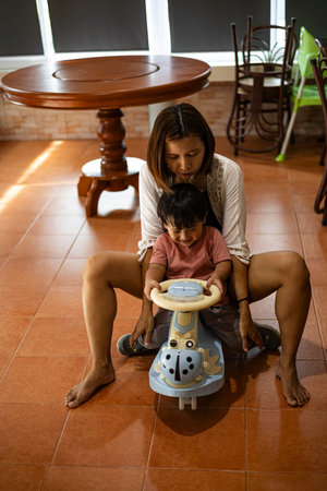 Mother And Toddler Riding A Toy Car In The House, Background for advertising and wallpaper in education and lifestyle scene.の写真素材