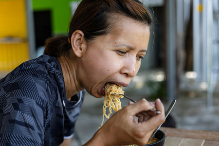 Woman Is Eating Instant Noodles, Tom Yum Kung Flavor, woman enjoying spicy Tom Yum Kung instant...