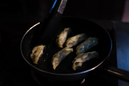 Gyozas Food Cooked In A Pan, Golden gyozas sizzle in a pan, steam rising with a savory aroma that fills the air, perfect for a delicious photo or a culinary delight showcase.の写真素材