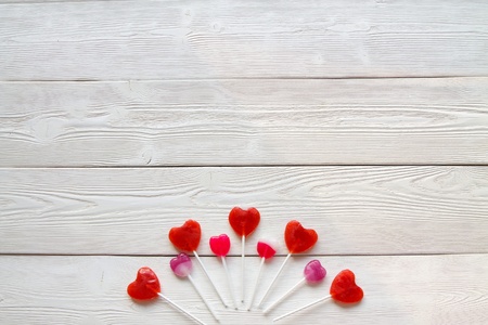 Flatlay: red and pink lollipops on a white wooden boardsの写真素材
