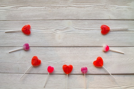 Flatlay: red and pink lollipops on a white wooden boardsの写真素材