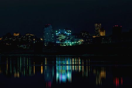 Night city view with lots of lights and its reflection in a river water