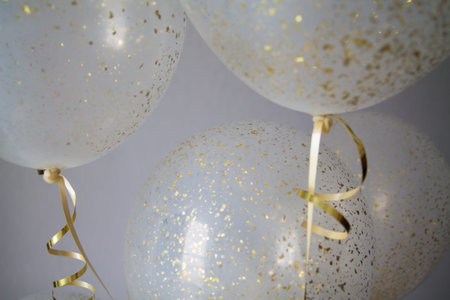 a bunch of transparent balloons with golden dust within on a white blurry background