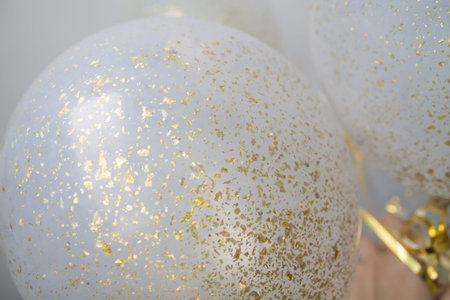 a bunch of transparent balloons with golden dust within on a white blurry background