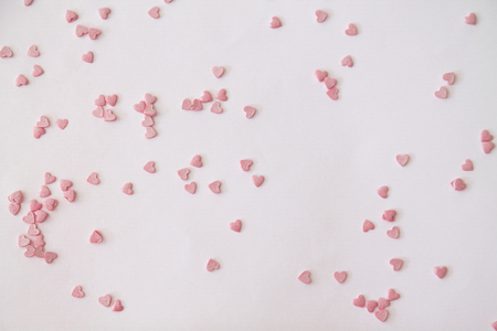 for St Valentine: White surface covered with multiple red and pink heart shaped paper confetti as a romantic background compositionの写真素材