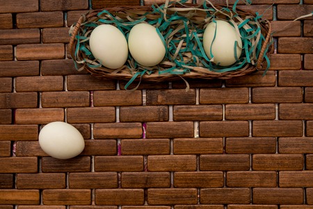 Easter eggs in basket on wooden background, top viewの写真素材
