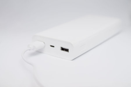 White power bank for charging mobile devices on white background. White smart phone charger with...