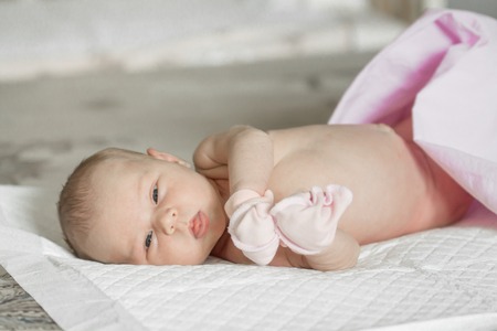 Closeup portrait of cute newborn baby lying down in the bed at home, smiling face, happy childhood, new life conceptの写真素材