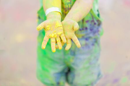 Hands, Palms of small children covered in green, yellow Holi festival colorsの写真素材