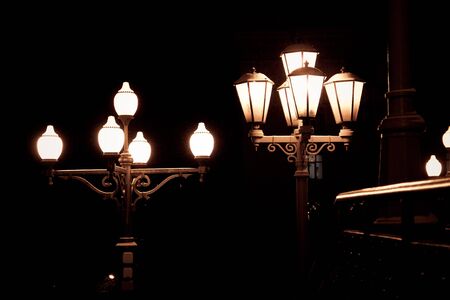 Old street electric lights at night on black background as little source of lightの写真素材