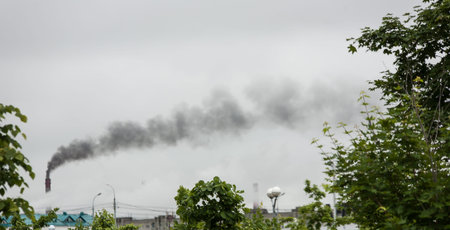 industrial chimneys with heavy smoke causing the air pollution during foggy weather with green...