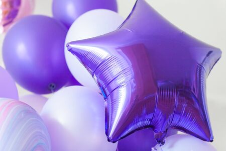 Flying round lilac and deep purple star balloons on a light gray background while celebration. Birthday background with ballons.の写真素材