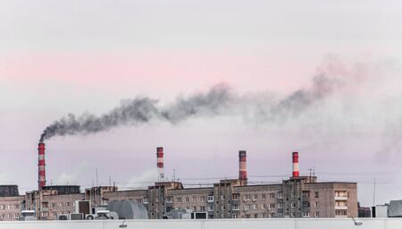 A panoramic view of industrial chimneys with black smoke and toxic poisonous gases during the sunsetの写真素材