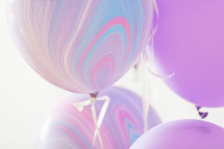 Flying purple and violet balloons on a light gray background while celebration. Birthday background with ballons.の写真素材
