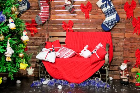 Christmas background theme with christmas toys on Christmas tree, pillows on red sofa and knitted socks on wooden wallの写真素材