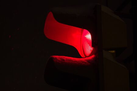close up of red traffic light during the snowfall in the eveningの写真素材