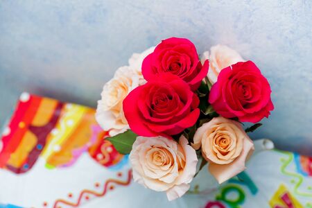 Romantic bouquet of red and creme beige roses as a gift to st. Valentine holiday on colorful table and gray backgroundの写真素材