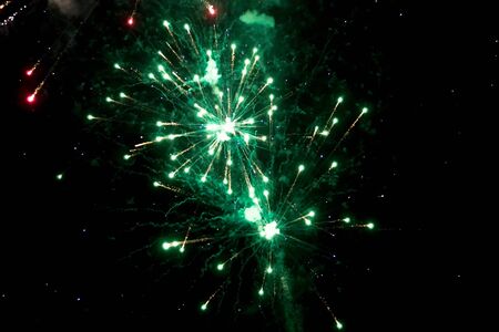 Green and aquamarine firework sparkles with beautiful smoke on black background during a holiday inthe eveningの写真素材
