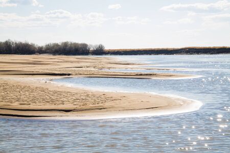 a river bank with sand dunes seen because of shallow waterの写真素材