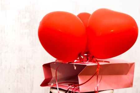 Copy space with a pink gift box and red heart shaped balloons on white backgroundの写真素材
