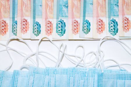 blue medical masks lying opposite lots of russian rubles banknotes as expenses concept during the coronavirus covid19 pandemicの写真素材