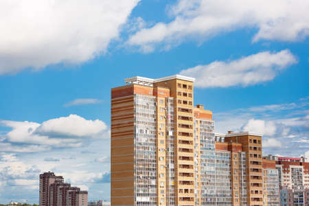 New block of modern apartments with balconies and blue sky with white fluffy clouds in the backgroundの写真素材