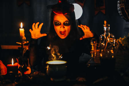 Little girl witch making magic potion at Halloween night with candles around her. Horror.の写真素材