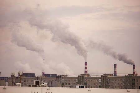 industrial chimneys with heavy smoke causing air pollution on gray sky backgroundの写真素材