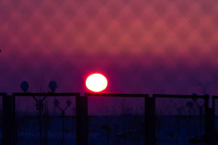 Blurred magenta and purple colored sunset through metal barsの写真素材