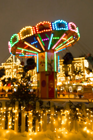 Defocused vertical pic of people ride carousel on Christmas with evening lightsの写真素材