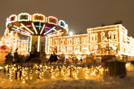 Defocused merry-go-round on Christmas with lights and bokeh on snowy eveningの写真素材