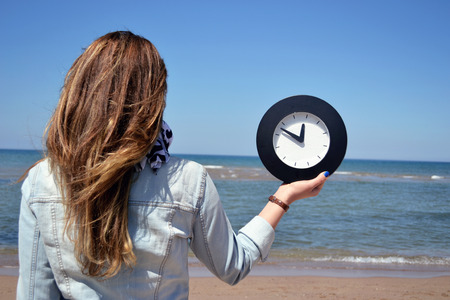 beautiful young woman holding a clockの写真素材