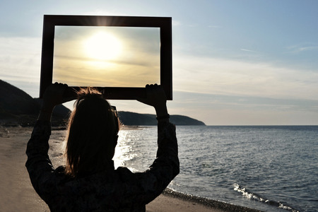 Beautiful woman holding an empty frameの写真素材